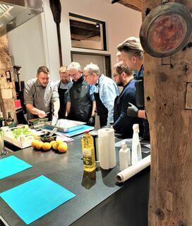 Gruppe von Freunden schneidet Zutaten und kocht gemeinsam bei einem privaten Kochkurs